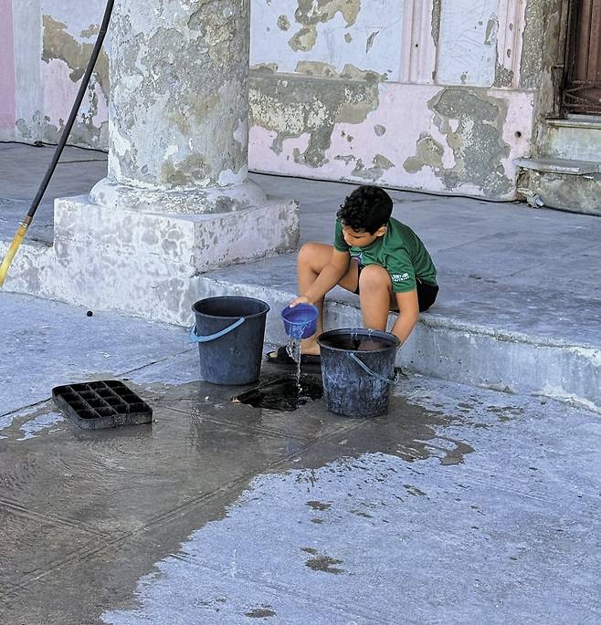 지난 22일 쿠바 아바나에서 한 아이가 상수도관에서 물을 퍼올리고 있다./박국희 특파원