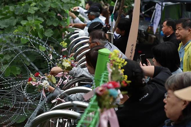 2024년 10월 경기도 동두천시 상봉암동 옛 성병관리소에서 동두천성병관리소 철거 저지를 위한 공동대책위원회(공대위) 주최로 철거에 반대하는 문화제가 열려 참가자들이 건물 들머리에 ‘평화의꽃’을 꽂고 있다. ‘유령 연구’의 지은이 그레이스 조는 공대위의 천막 농성장에 두 번 방문했다고 한국어판 서문에 썼다. 이종근 선임기자 root2@hani.co.kr