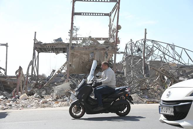 4일 이란 테헤란에서 한 남자가 오토바이를 타고 파괴된 건물들을 지나가고 있다. /연합뉴스