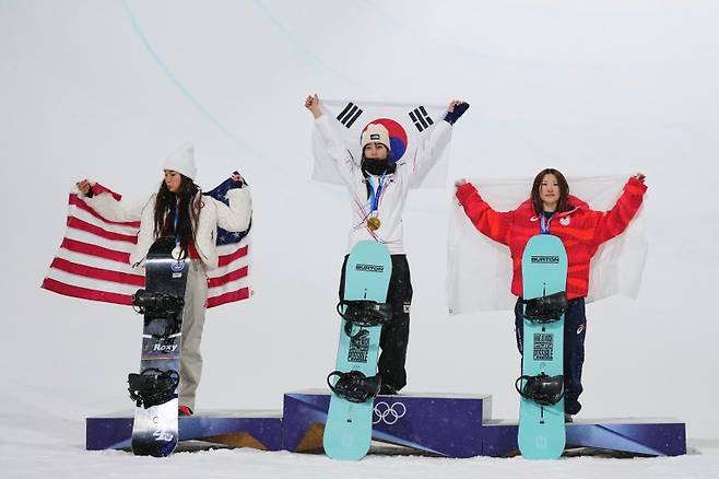 최가온(가운데), 클로이 김(왼쪽), 오노 미츠키(오른쪽)가 지난 2월 12일(현지시간) 이탈리아 리비뇨 스노파크에서 열린 2026 밀라노·코르티나담페초 동계올림픽 스노보드 여자 하프파이프 시상식에서 자국의 국기를 들고 있다. 뉴시스