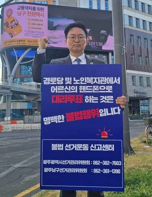 ▲31일 광주 남구 백운 교차로에서 정진욱 더불어민주당 국회의원(광주 동남갑)이 대리투표 등 불법행위와 부정선거신고센터 번호가 적힌 손팻말을 들고 1인 시위하고 있는 모습.2026.03.31ⓒ정진욱 페이스북 갈무리