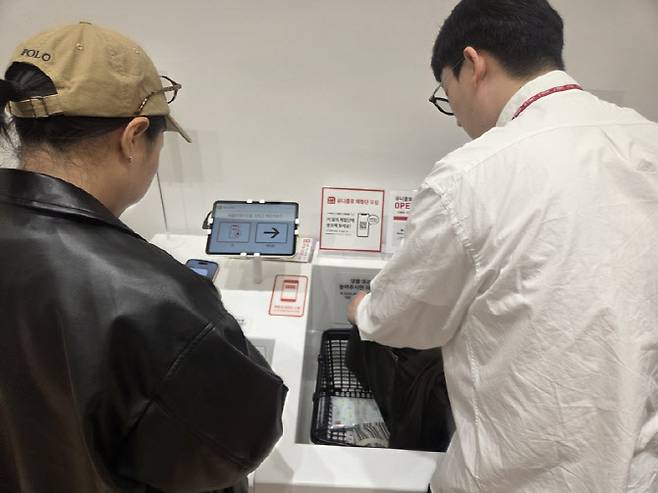 무인 계산대 이용 방법을 듣고 있는 고객. 바구니를 올리면 자동으로 상품 품목들이 인식된다. (사진=한전진 기자)