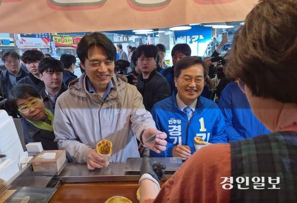 더불어민주당 경기도지사 경선 후보인 한준호 후보(왼쪽)와 김동연 후보가 6일 수원 못골시장 한 분식집에서 호떡을 사 먹고 있다. 2026.4.6 /김태강 기자 think@kyeongin.com
