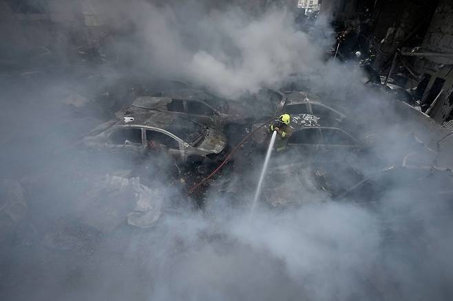 8일(현지시간) 레바논 베이루트의 한 아파트 건물이 이스라엘군의 공습을 받아 파괴된 가운데, 소방대원이 잔해 속에서 불길을 잡고 있다. AP=연합뉴스