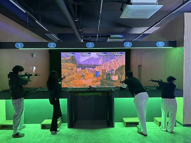 경기도사격테마파크 가상사격장에 마련된 스크린 사격장에서 이용객들이 스크린을 향해 총을 쏘고 있다.