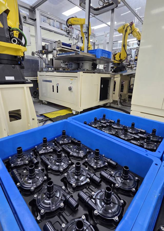 지엠비코리아 창원2공장 조립 라인에서 생산된 전동식 워터펌프 스테이터 부품이 파란 트레이에 가득 담겨 있다. 뒤편으로 산업용 로봇암이 쉼 없이 가동되고 있다.