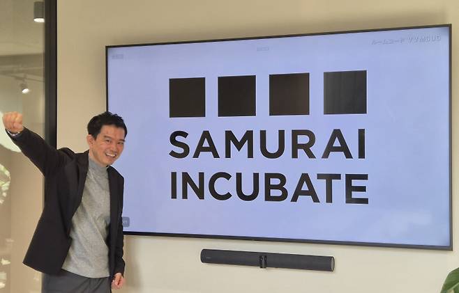 사카키바라 켄타로 사무라이 인큐베이트 대표가 회사 로고 앞에서 포즈를 취하고 있다. (사진=박소영 기자)
