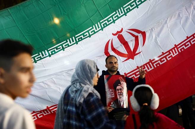 한 남성이 8일(현지시간) 이란 테헤란에서 열린 마지드 하데미 이슬람혁명수비대(IRGC) 정보조직 수장 장례식에서 고 알리 하메네이 이란 최고지도자의 사진을 들고 있다. 하데미는 최근 공습으로 숨진 것으로 전해졌다. 로이터 연합뉴스