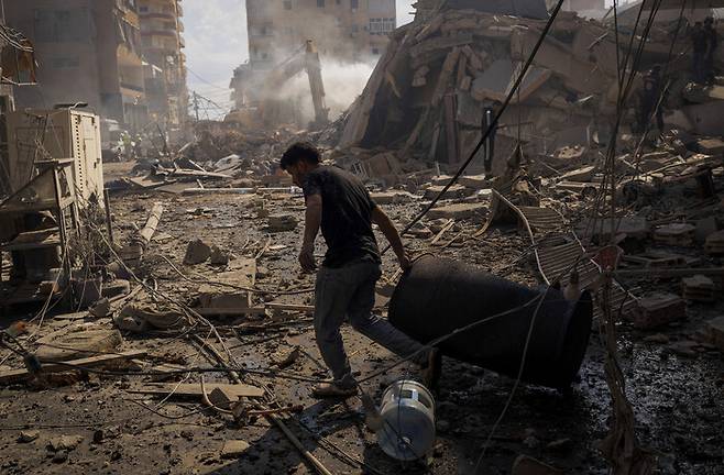지난 8일 레바논 티레에서 이스라엘의 공습 이후 잔해가 흩어진 현장에서 한 남성이 드럼통을 끌고 있다. 로이터 연합뉴스