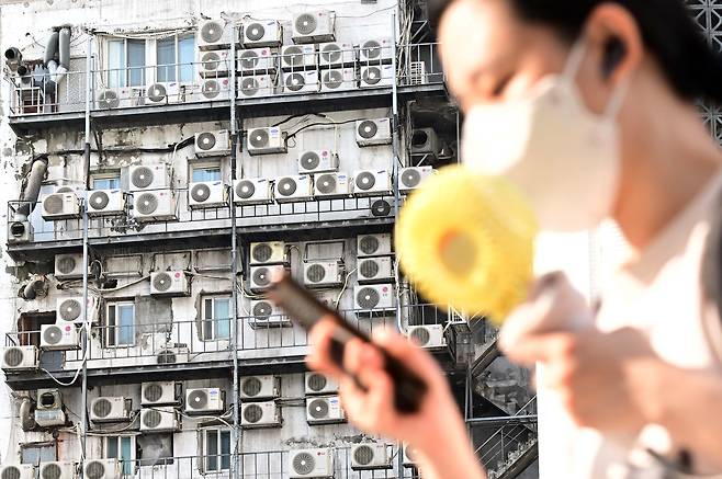 한 시민이 서울 중구 남대문 인근에 있는 건물 외벽에 줄지어 걸린 에어컨 실외기 앞을 지나가고 있다. 이상섭 기자