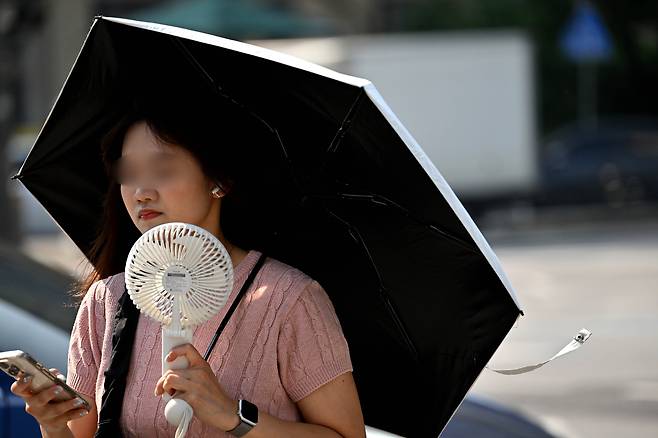 서울 종로구 세종대로 사거리에서 한 시민이 양산으로 뜨거운 햇살을 가리며 출근길을 서두르고 있다. 임세준 기자