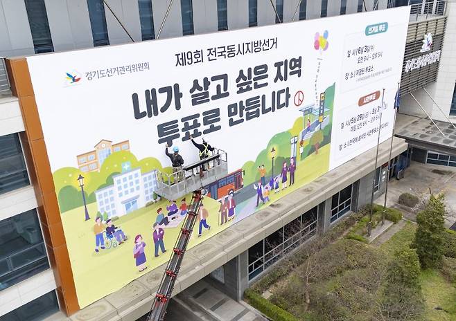 제9회 전국동시지방선거를 앞둔 지난 9일 경기도 수원시 영통구 경기도선거관리위원회 청사 외벽에 관계자들이 투표참여를 독려하는 대형 현수막을 설치하고 있다. 뉴스1