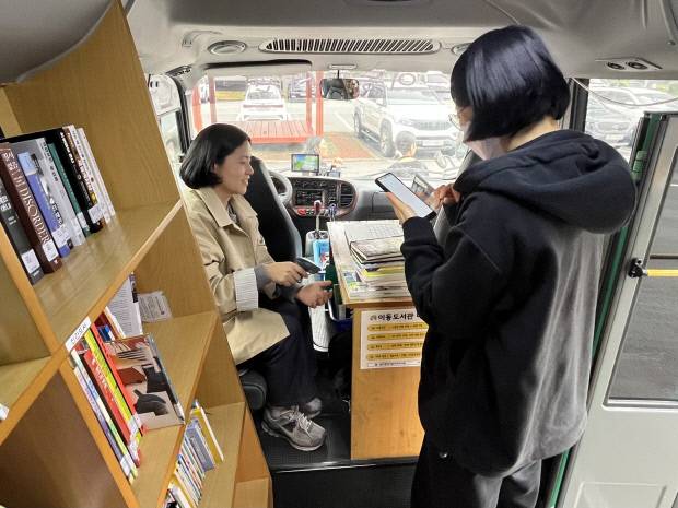 지난 10일 광주시 서구 풍암동 호반중흥아파트단지를 찾은 이동도서관 버스에서 이용객이 도서를 대출하고 있다. /윤준명 기자 yoon@kwangju.co.kr