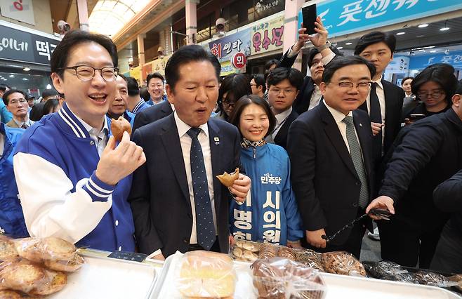 더불어민주당 정청래 대표가 3월 23일 오후 경남 양산시 중부동 양산남부시장에서 찹쌀도넛을 먹고 있다. 왼쪽은 김경수 경남지사 후보./연합뉴스