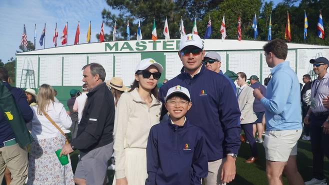 마스터스 부대 행사인 ‘드라이브, 칩 앤드 퍼트’에서 우승한 로이 문(가운데)이 6일(현지 시간) 미국 오거스타 내셔널GC 1번 홀의 대형 스코어보드 앞에서 부모와 함께 기념 촬영을 하고 있다. 오거스타=양준호 기자