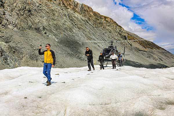 빙하 위에 착륙한 헬리콥터에서 내리는 탐승객들.