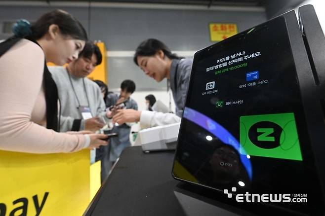 금융위원회가 주최하고 한국핀테크지원센터가 주관한 '코리아 핀테크 위크 2025'가 2025년 11월 26일 서울 서초구 aT센터에서 열렸다. 네이버페이 부스에서 관람객이 오프라인 단말기 N페이 커넥트에 대한 설명을 듣고 있다. 김민수기자 mskim@etnews.com