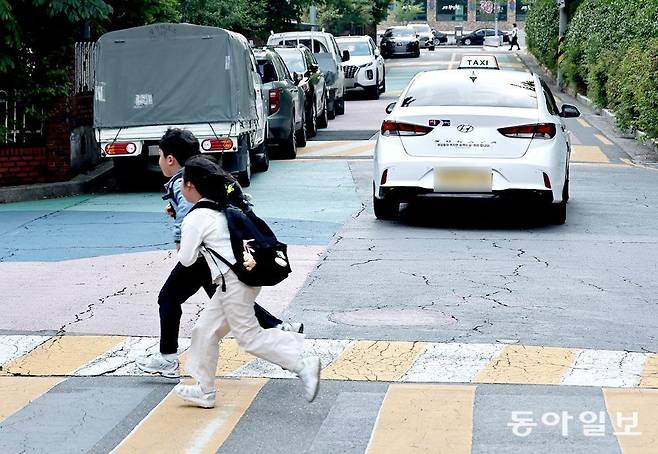 12일 오후 서울 노원구의 한 초등학교 인근 어린이 보호구역에서 초등학생들이 차 한 대만 지나갈 수 있는 폭의 이면도로를 뛰어 건너고 있다. 이 일대엔 보행로가 미비해 어린이가 차로로 다녀야 하는 이면도로가 적지 않아 사고가 반복되고 있다. 양회성 기자 yohan@donga.com