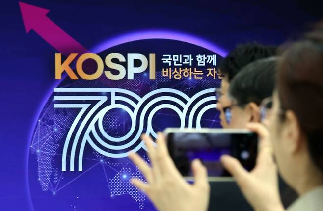 사상 처음으로 코스피 7000p를 돌파한 지난 6일 부산 남구 부산국제금융센터 내 한국거래소 홍보관에서 열린 축하행사에 참석한 한 관계자가 휴대전화로 촬영하고 있다. 사진=뉴시스