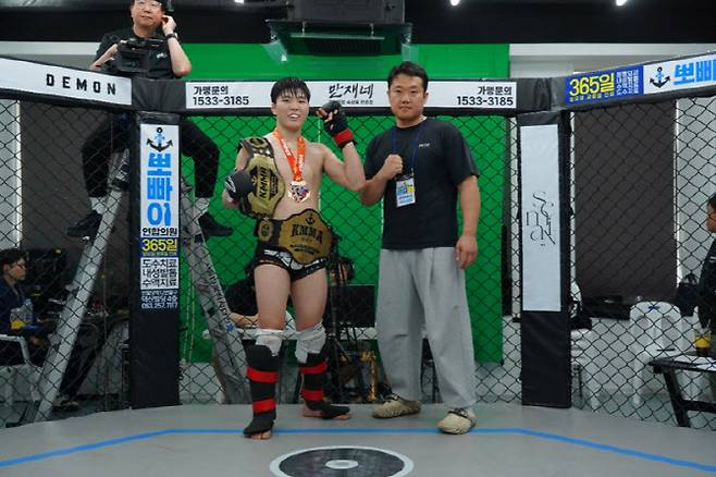 KMMA 현 페더급 챔피언 임유홍(왼쪽)이 라이트급 타이틀전에서 승리하며 두 개의 벨트를 걸고 쉴드MMA 이역열 관장과 기념사진을 찍고 있다. 사진=KMMA