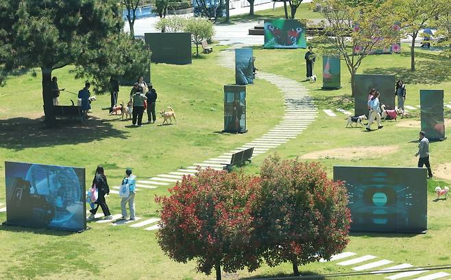 지난달 부산 해운대구 부산시립미술관 야외 조각 공원에서 시민들이 '루프 랩 부산'의 영상 전시 '디지털 서브컬처: 모두가 창조자' 작품을 살펴보고 있다. /연합