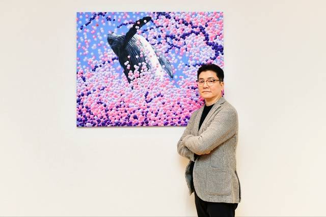 전홍준 어트랙트 대표가 경기 하남시에 자리한 어트랙트 미사트레이닝센터 1층 카페에서 사진촬영을 하고 있다. 전 대표 뒤의 그림은 이동욱 작가의 작품으로, 고래는 소속사 아티스트인 바비킴의 ‘고래의 꿈’을, 분홍색과 보라색 풍선은 피프티피프티의 퍼스널 컬러를 상징한다. 하남=박성훈 기자