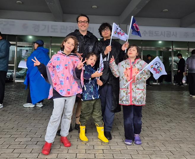 올리버 한츠(뒷줄 왼쪽)씨 가족이 20일 수원FC위민과 북한 내고향여자축구단의 경기가 열릴 경기 수원종합운동장에서 수원과 내고향 모두의 깃발을 흔들며 즐거워하고 있다. 박성국 기자
