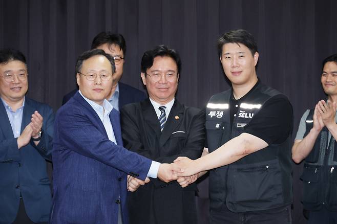 지난 20일 경기도 수원시 장안구 경기고용노동청에서 열린 삼성전자 임금협상을 마친 후 여명구 삼성전자 DS(디바이스솔루션·반도체 사업 담당) 피플팀장과 최승호 삼성그룹 초기업노동조합 삼성전자지부 위원장이 잠정 합의안에 서명한 후 김영훈 고용노동부 장관과 손을 맞잡고 있다. 연합뉴스