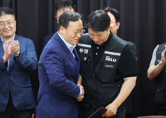 20일 경기도 수원시 장안구 경기고용노동청에서 열린 삼성전자 임금협상을 마친 후 여명구 삼성전자 DS(디바이스솔루션·반도체 사업 담당) 피플팀장과 최승호 삼성그룹 초기업노동조합 삼성전자지부 위원장이 잠정 합의안에 서명한 후 손을 맞잡고 있다. 연합뉴스