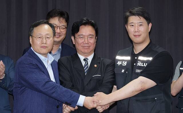 20일 경기도 수원시 장안구 경기고용노동청에서 열린 삼성전자 임금협상을 마친 후 여명구 삼성전자 DS(디바이스솔루션·반도체 사업 담당) 피플팀장과 최승호 삼성그룹 초기업노동조합 삼성전자지부 위원장이 잠정 합의안에 서명한 후 김영훈 고용노동부 장관과 손을 맞잡고 있다. 연합뉴스