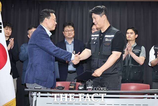 지난 20일 경기도 수원시 장안구 경기고용노동청에서 열린 삼성전자 임금협상을 마친 후 여명구 삼성전자 DS 피플팀장(왼쪽)과 최승호 삼성그룹 초기업노동조합 삼성전자지부 위원장이 잠정 합의한에 서명한 후 손을 맞잡고 있다. /뉴시스