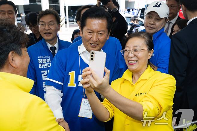 우상호 강원특별자치도지사 후보와 김중남 강릉시장 후보 지원유세에 나선 정청래 더불어민주당 대표가 22일 강원 강릉시 주문진 시장에서 상인과 기념 촬영을 하고 있다. 2026.5.22 ⓒ 뉴스1 유승관 기자
