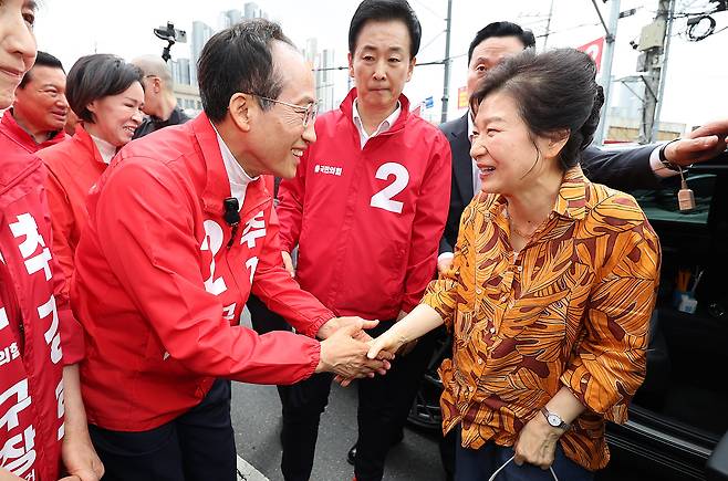 박근혜 전 대통령이 23일 대구 북구 칠성시장에 도착해 추경호 국민의힘 대구시장 후보와 악수하고 있다. /뉴시스