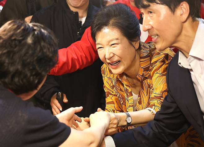 박근혜 전 대통령이 23일 오후 대구 북구 칠성시장을 찾아 추경호 국민의힘 대구시장 후보 등 일행과 함께 이동하며 상인과 인사 나누고 있다./뉴스1