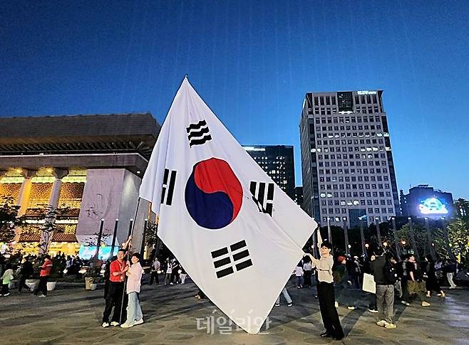 23일 저녁 서울 광화문광장 내 '감사의 정원'에서 시민들이 대형 태극기를 배경으로 기념사진을 촬영하고 있다. ⓒ데일리안 진현우 기자