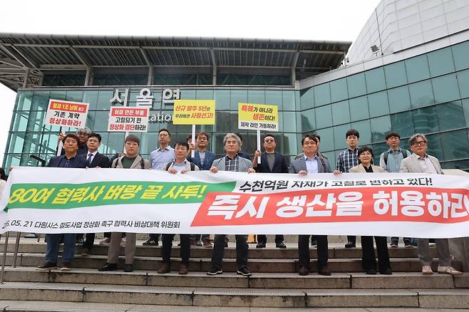다원시스 철도 사업 정상화 촉구 협력사 비상대책위원회가 21일 서울역 광장에 집결해 “수천억 원 자재가 고철로 변하고 있다! 즉시 생산을 허용하라”고 촉구하고 있다. 철도 협력사 비대위 제공