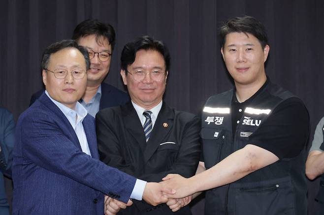 20일 경기도 수원시 장안구 경기고용노동청에서 열린 삼성전자 임금협상을 마친 후 여명구 삼성전자 DS(디바이스솔루션·반도체 사업 담당) 피플팀장과 김영훈 고용노동부 장관, 최승호 삼성그룹 초기업노동조합 삼성전자지부 위원장이 잠정 합의한에 서명한 후 손을 맞잡고 있다. (사진=뉴시스)