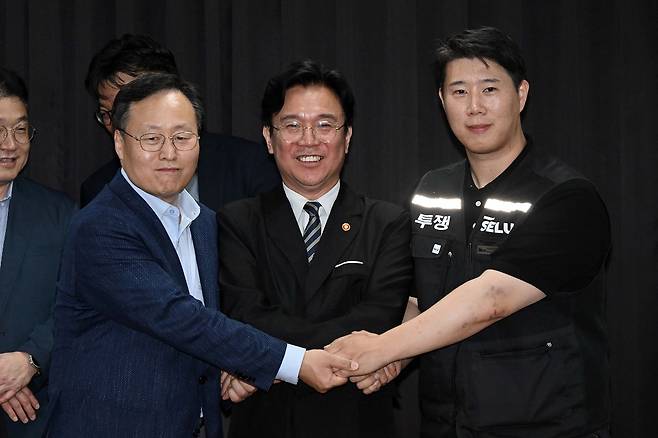 지난 20일 경기도 수원시 장안구 경기고용노동청에서 열린 삼성전자 임금협상을 마친 후 여명구 삼성전자 DS 피플팀장(왼쪽)과 김영훈 고용노동부 장관(가운데), 최승호 삼성그룹 초기업노동조합 삼성전자지부 위원장(오른쪽)이 잠정 합의한에 서명한 후 손을 맞잡고 있다. 뉴스1