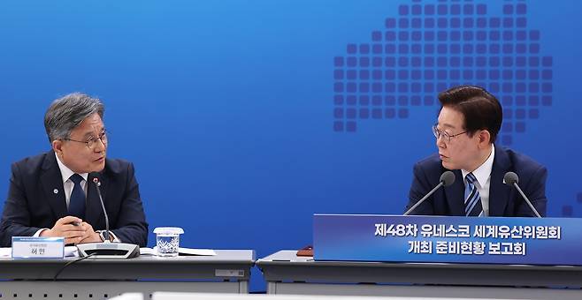 이재명 대통령이 27일 부산 해운대구에서 열린 제48차 유네스코 세계유산위원회 개최 준비 현황 보고회에서 허민 국가유산청장과 대화하고 있다. 이날 이 대통령은 최근 BTS 부산 공연으로 불거진 ‘숙박비 바가지’ 문제를 지적했다. 연합뉴스