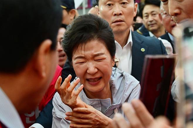 박근혜 전 대통령이 27일 경남 진주 대안동 진주중앙시장을 찾아 박완수 국민의힘 경남도지사 후보, 한경호 진주시장 후보 지원유세를 하며 시민과 악수한 뒤 고통스러워 하고 있다. 뉴스1