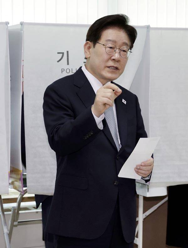 이재명 대통령이 지난 29일 서울 종로구 삼청동 주민센터의 사전투표 기표소에서 나와 선거사무원들에게 기표 도장 관련 문의를 하고 있다. 연합뉴스