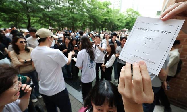 6·3 지방선거 본투표일인 3일 서울 송파구 잠실2동 6투표소에서 투표용지 부족으로 대기하던 한 유권자가 마감시간 후 대기번호표를 들어 보이고 있다. 연합뉴스