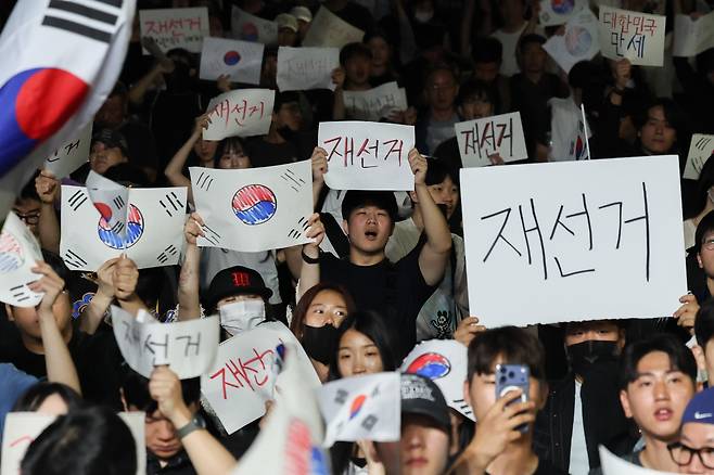 6일 새벽 서울 송파구 올림픽공원 핸드볼경기장 앞에서 시민들이 태극기와 ‘재선거’라고 적힌 손팻말을 들고 구호를 외치고 있다. / 고운호 기자