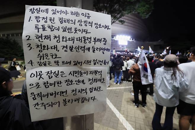 6일 새벽 서울 송파구 올림픽공원 핸드볼경기장 앞에서 시민들이 태극기와 ‘재선거’라고 적힌 손팻말을 들고 선거 관리 부실에 항의하고 있는 가운데 정치 집회 간주를 경계하는 문구가 붙어있다. / 고운호 기자