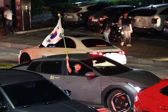 6일 새벽 서울 송파구 올림픽공원에서 한 시민이 태극기를 흔들며 '재선거' 구호를 외치고 있다. / 고운호 기자
