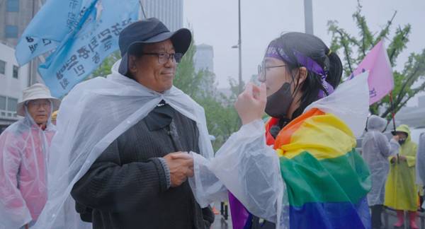 ▲ 영화 '남태령'에서 전주환 전국농민회 부경연맹 사무처장이 무지개 깃발을 두른 말벌동지 활동가와 악수하고 있다. 사진=시네마 달 제공