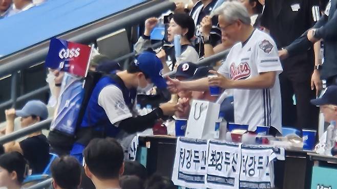 젠슨 황(오른쪽) 엔비디아 CEO가 7일 잠실구장에서 열린 2026 KBO리그 키움과 두산전에서 맥주 판매원에게 5만 원짜리 지폐를 건넨 뒤 격려하고 있다. 김형준 기자