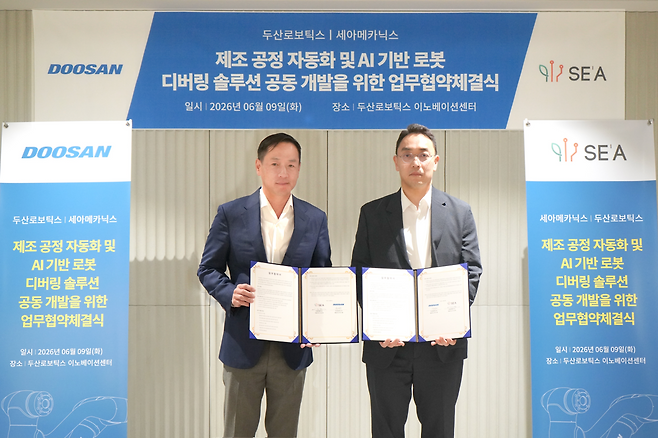 이성욱 세아메카닉스 대표와 박인원 두산로보틱스 사장이 9일 두산로보틱스 이노베이션센터에서 ‘제조 공정 자동화 및 AI 기반 로봇 디버링 솔루션 공동 개발’을 위한 업무협약(MOU)을 체결한 뒤 협약서를 들고 기념촬영을 하고 있다.(세아메카닉스 제공)