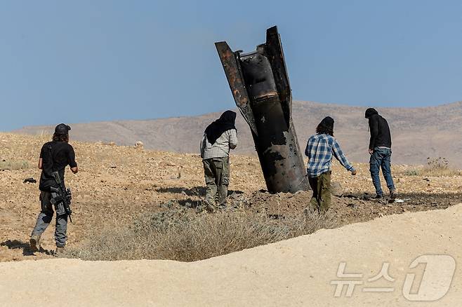 8일(현지시간) 이스라엘 점령지 요르단강 서안 중부에서 이스라엘 정착민들이 이란의 미사일 공격 이후 땅에 박힌 미사일 잔해를 바라보고 있다. 2026.06.08. ⓒ 로이터=뉴스1
