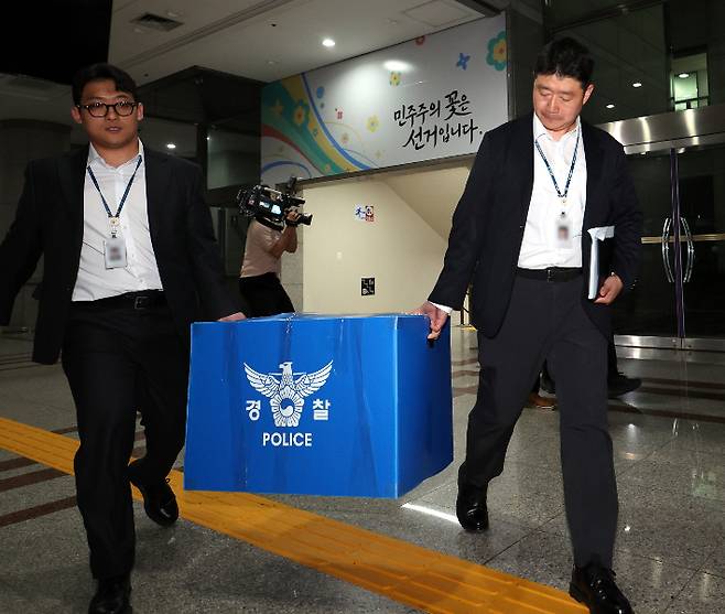 6·3 전국동시지방선거 투표용지 부족 사태를 들여다보고 있는 검경 합동수사본부 관계자들이 11일 경기도 과천 중앙선거관리위원회에서 압수수색을 마친 뒤 압수품을 들고 건물을 나서고 있다. 연합뉴스